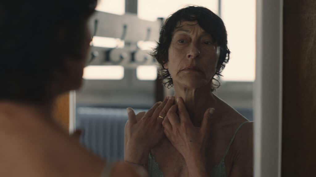 Une femme d'une soixantaine d'années se regarde dans le miroir